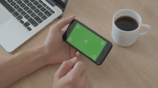 Крупный план мужских рук, касающихся смартфона за рабочим столом. Зеленый экран Chroma Key . — стоковое видео