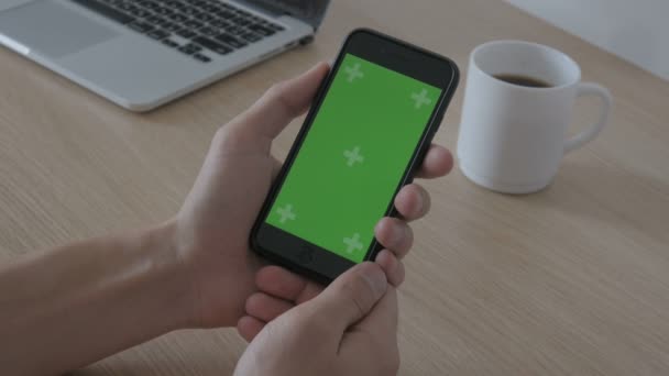Крупним планом чоловічі руки торкаються смартфона за робочим столом. Зелений екран Chroma Key . — стокове відео
