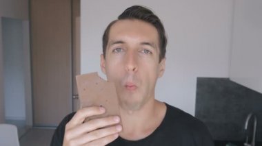 Genç adam yiyor çikolata bar evde mutfak