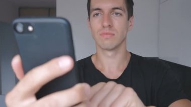 Genç adam agresif smartphone evde mutfakta kullanır..