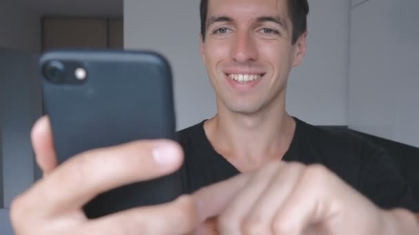 Hombre Joven Guapo Sonriendo Utiliza Smartphone Casa Cocina — Vídeo de stock