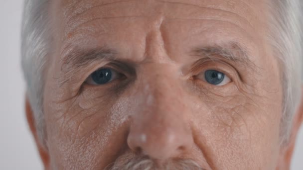 Senior férfi bajusz néz fehér háttér kamera közelről — Stock videók