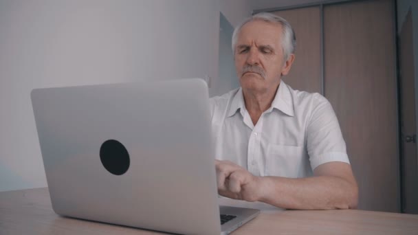 Homem Sênior de cabelos grisalhos com bigode trabalhando no laptop no escritório sentado à mesa — Vídeo de Stock