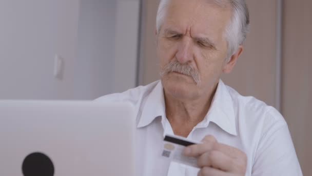Vista de cerca de hombre mayor de compras en línea en casa en el ordenador portátil, escribiendo el número de tarjeta de crédito — Vídeos de Stock