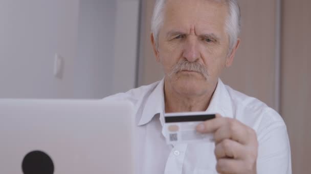 Senior man online shoping thuis op laptop, credit cardnummer typen — Stockvideo