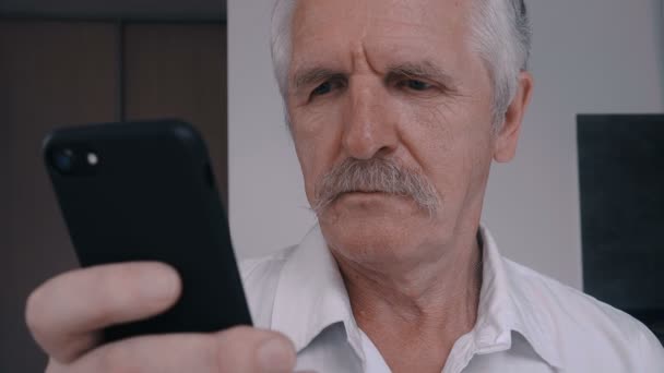 Close up van Senior man met snor met behulp van slimme telefoon thuis in de keuken — Stockvideo