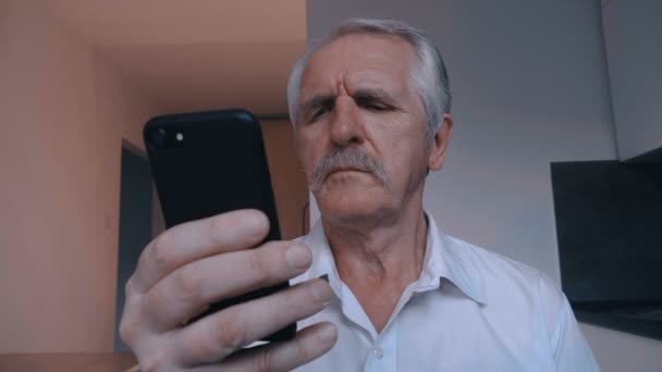 Retrato del hombre mayor con bigote usando teléfono inteligente en casa en la cocina — Vídeos de Stock