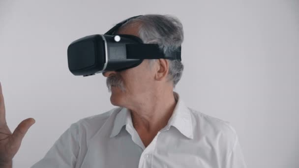 Senior man använder hans Vr-headset för att titta på en 360-video på vit bakgrund — Stockvideo