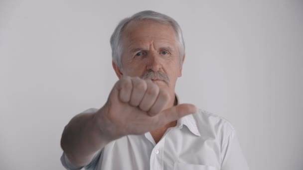 Сірошерстий старший чоловік показує великий палець вниз. Знак відмови — стокове відео