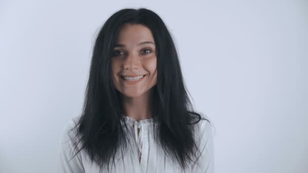 Retrato de mujer joven morena mirando y sonriendo a la cámara en el fondo blanco — Vídeos de Stock