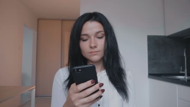 自宅でスマート フォンを使用して若い女性のブルネットの肖像画 — ストック動画