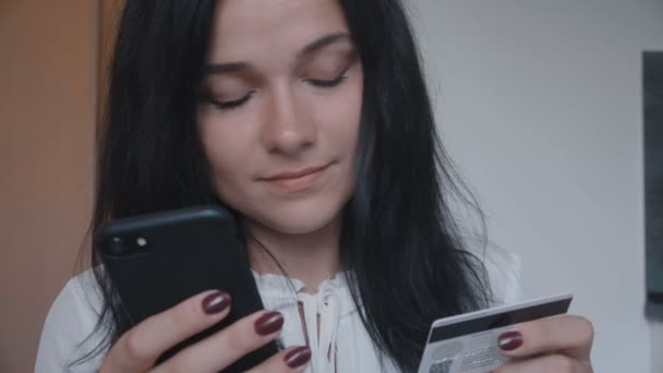 Jonge vrouw winkelen online met credit card en smartphone thuis — Stockvideo