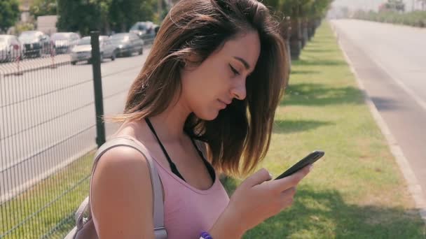 Porträt einer jungen Touristin, die an heißen Sommertagen im Tropenresort ihr Smartphone an der Stadtstraße benutzt — Stockvideo