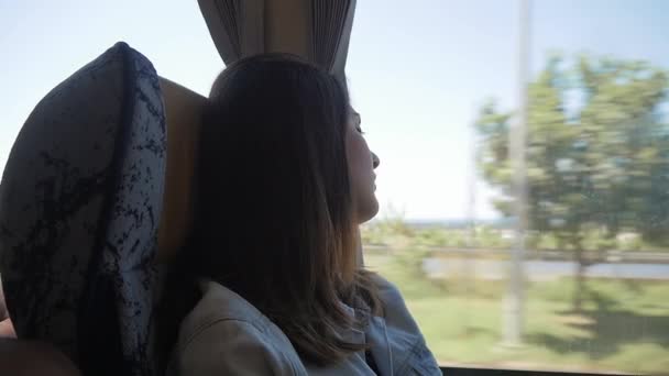 Ung brunett kvinna resor med buss, beundra utsikten genom fönstret — Stockvideo