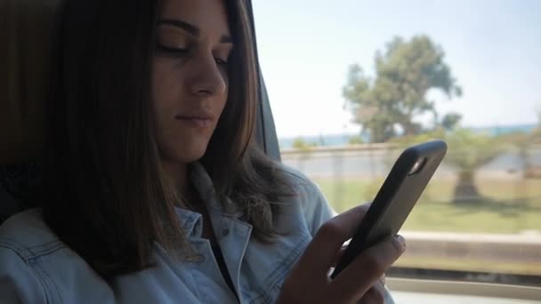 Νεαρή γυναίκα χρησιμοποιώντας smartphone κατά τη διαδρομή με το λεωφορείο — Αρχείο Βίντεο