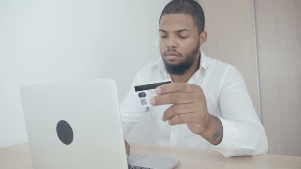 Afrikanska ung man handla online med kreditkort använder laptop hemma. — Stockvideo