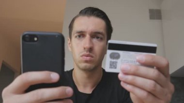 Kızgın genç adam online satın alma bir telefon ve bir kredi kartı ve aldatılmış duygu kullanır. Başarısız Internet alışveriş. Kredi kartı dolandırıcılığı