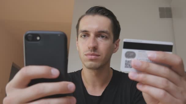 Šťastný mladý muž nákup online používá telefon a kreditní karty doma kuchyň nákupní internet používá smartphone — Stock video