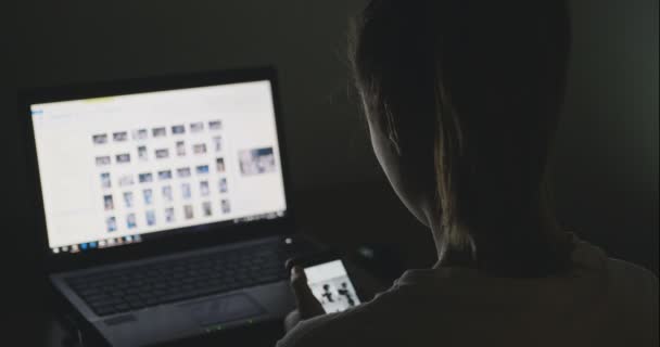 Jovem mulher de negócios trabalhando com laptop e smartphone em casa tarde da noite — Vídeo de Stock