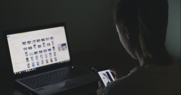 Jonge vrouw desingner werken met laptop en smartphone thuis laat in de avond — Stockvideo