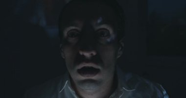 Genç adam bir korku video ya da Tv veya bilgisayar monitörü evde film izlerken kapatın. Korkmuş gibi görünüyor.