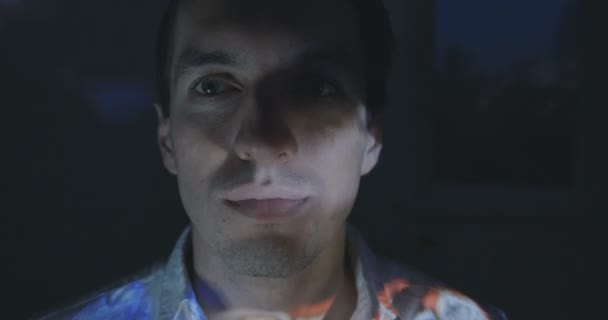 Close up van een jonge man, kijken naar een video of film op Tv of de computermonitor van een thuis. Reflectie op zijn gezicht. — Stockvideo