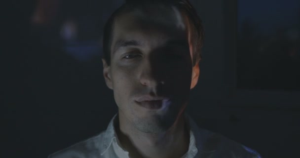 Close-up van gezicht van jonge man met reflectie van video terwijl het letten van film op Tv of de computermonitor van een thuis. — Stockvideo
