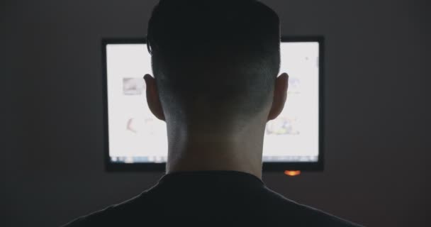 Vue arrière du jeune homme surfant sur internet la nuit — Video