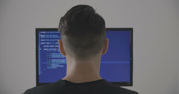 Ervaren programmeur werkt op een nieuw programma. Jongeman hacker schrijft de broncode van de software. Achteraanzicht. — Stockvideo