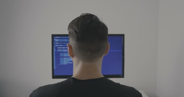 Upplevt det programmerare fungerar på ett nytt program. Ung man hacker skriver källkoden till programvaran. Bakifrån. — Stockvideo