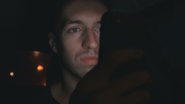 男子使用智能手机 而坐在汽车上的道路上 在夜间城市 — 图库视频影像