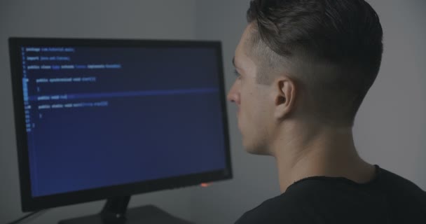 Молодой человек программист пишет код во время работы на компьютере в офисе — стоковое видео