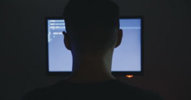 Programcı inşaat üstünde yeni bir program deneyimli. Genç adam hacker karanlık oda, yazılım kaynak kodu yazıyor. Arkadan görünüm.