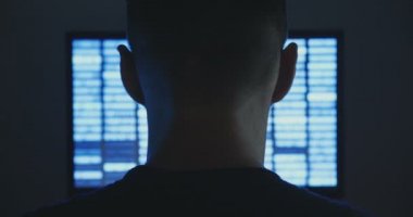 Erkek hacker ekran karanlık office odasında ikili kodu içeren bir bilgisayarda çalışır.