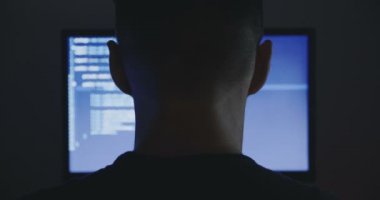 Programcı inşaat üstünde yeni bir program deneyimli. Genç adam hacker karanlık oda, yazılım kaynak kodu yazıyor. Arkadan görünüm.