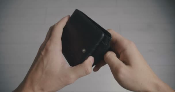 Gros plan d'une main d'homme tenant un portefeuille en cuir vide sans argent. Le concept de pauvreté — Video