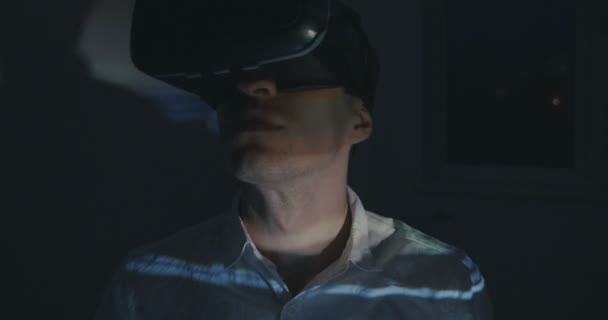 Hombre joven viendo con realidad virtual VR dobladillo en la noche en casa — Vídeo de stock