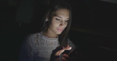 Geceleri smartphone kullanarak arabada oturan güzel kadın.