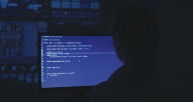 Kadın programcı inşaat üstünde yeni bir program deneyimli. Genç kadın hacker karanlık oda, yazılım kaynak kodu yazıyor. Arkadan görünüm.