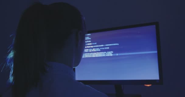 Portrait d'une jeune femme programmeuse pirate informatique travaillant la nuit dans un centre de données. Vue arrière . — Video