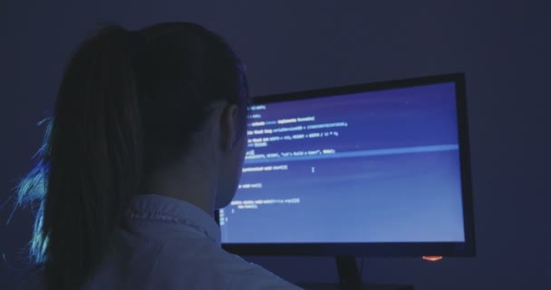 Portret młodej kobiety haker programista pracuje przy komputerze w nocy w centrum danych. Widok z tyłu. — Wideo stockowe