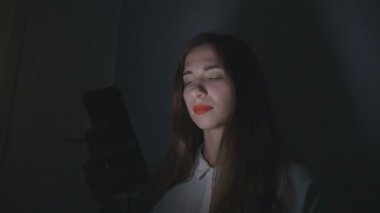 Genç kadın smartphone evde geceleri odasında kullanır.