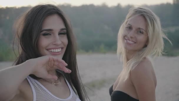 Hermosa joven morena y su amiga rubia bailando sonriendo y divirtiéndose en vacaciones — Vídeo de stock