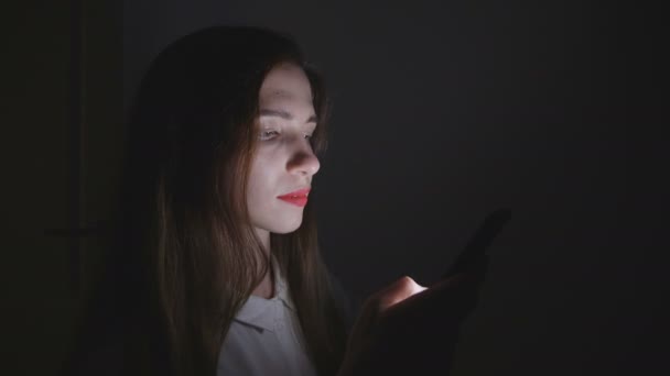 Νεαρή γυναίκα χρησιμοποιεί smartphone τη νύχτα στο σπίτι στο δωμάτιό της. — Αρχείο Βίντεο