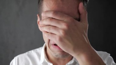 Genç adam eliyle yüzünü kaplayan ağlıyor çaresizlik içinde. Gözyaşlarıyla ağlayarak iş adamı. İş çöküşü.