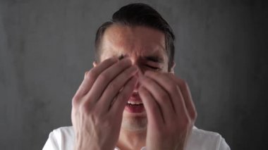 Genç adam eliyle yüzünü kaplayan ağlıyor çaresizlik içinde. Gözyaşlarıyla ağlayarak iş adamı. İş çöküşü.