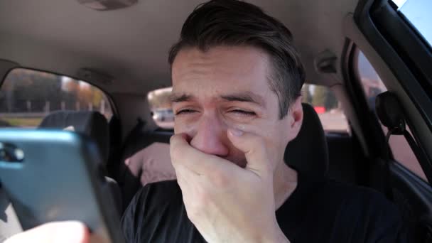 Грустный отчаявшийся мужчина читает плохие смс на смартфоне плачущий в машине — стоковое видео