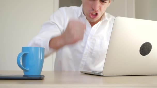 Gestresste ondernemer met woede verslaat zijn vuist op tafel. Gemorst thee uit de beker op de laptop. Vul de laptop met water. — Stockvideo