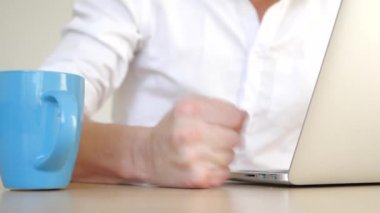 Öfke ile stresli iş adamı masaya yumruk atıyor. Dökülen çay Kupası laptop. Belgili tanımlık laptop su ile doldurun.