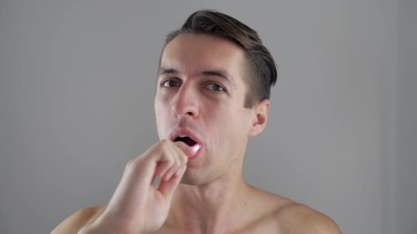 Young man brushing his teeth in bathroom and stop becuse of a tooth pain — Stock Video